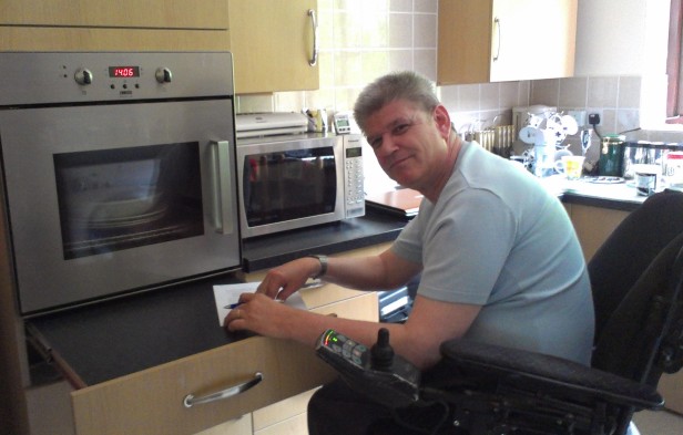 Wheelchair user in his accessible kitchen